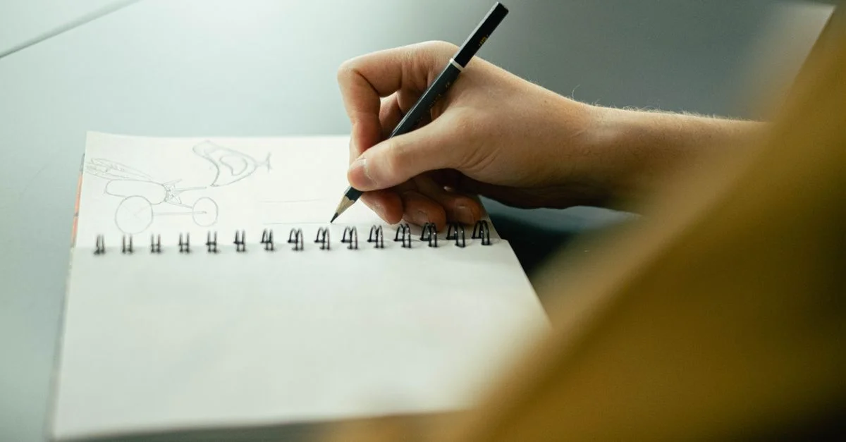 Dessin à la main dans un carnet avec un crayon, axé sur la créativité et la planification.
