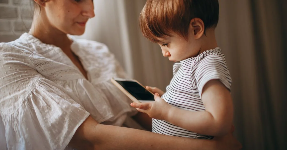 Un tendre moment entre une mère et son enfant qui explorent ensemble un smartphone, profitant d'un moment en famille.