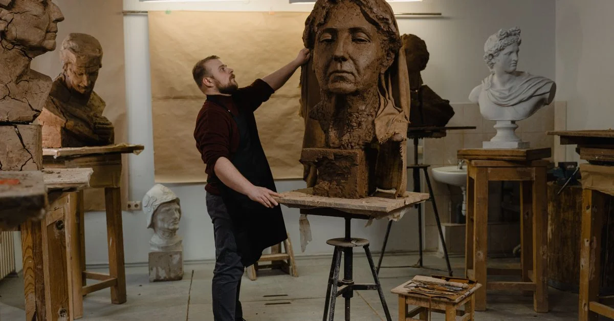 Un sculpteur masculin travaillant avec diligence dans un atelier d'art, créant un grand buste en argile.