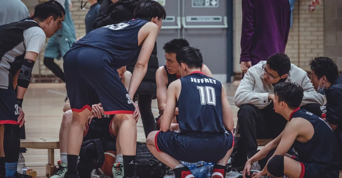 Des joueurs de basket-ball discutent de stratégie pendant une pause dans une salle de sport.