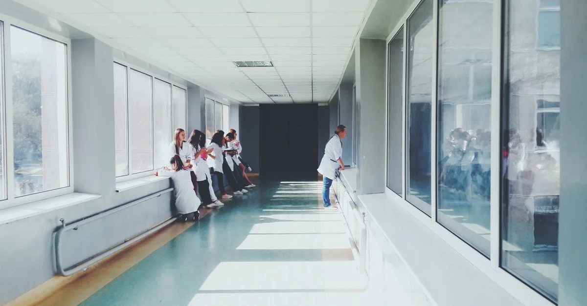 Un couloir d'hôpital bien éclairé avec du personnel médical en blouses blanches, transmettant un environnement de soins de santé professionnel.