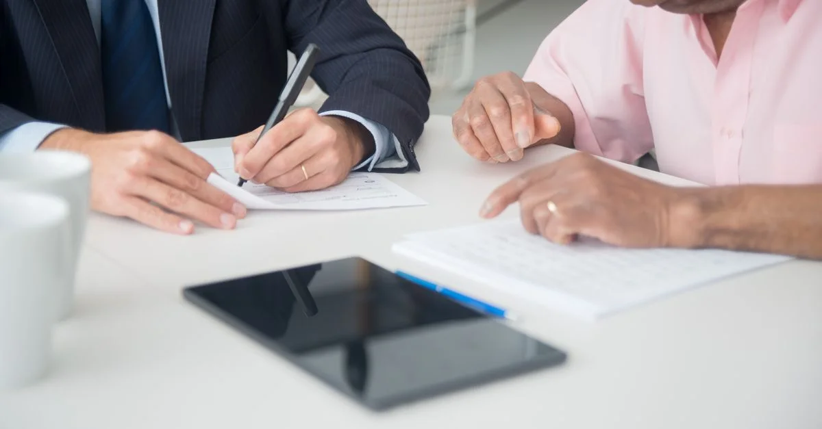 Deux professionnels discutent et signent des documents lors d'une réunion d'affaires.