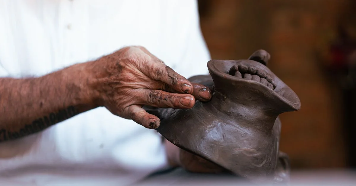Gros plan sur un artisan talentueux créant un masque en argile avec des mouvements de main précis dans un atelier.